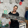 A person holding a wooden single plank sign with personalized text that reads 'This is us - Our Life, Our Story, Our Home.'